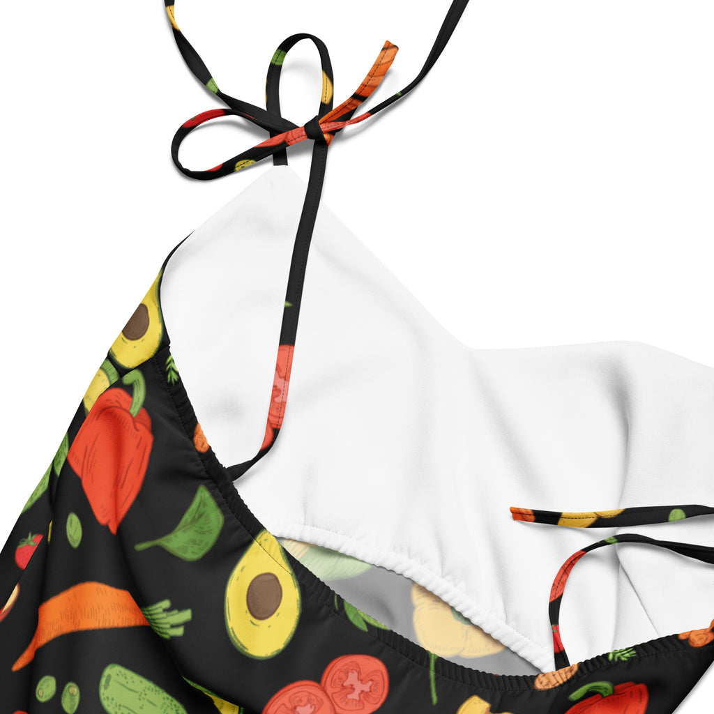 Black halter top bikini with vibrant vegetable print and white interior lining complementing women’s vegetable and fruit slip dress