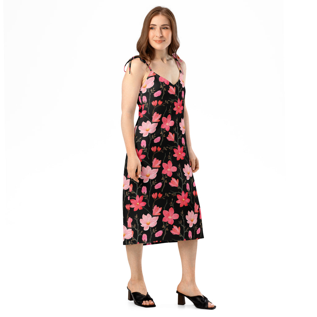 A black floral midi slip dress with pink blossoms and adjustable tie straps featuring a built in bra