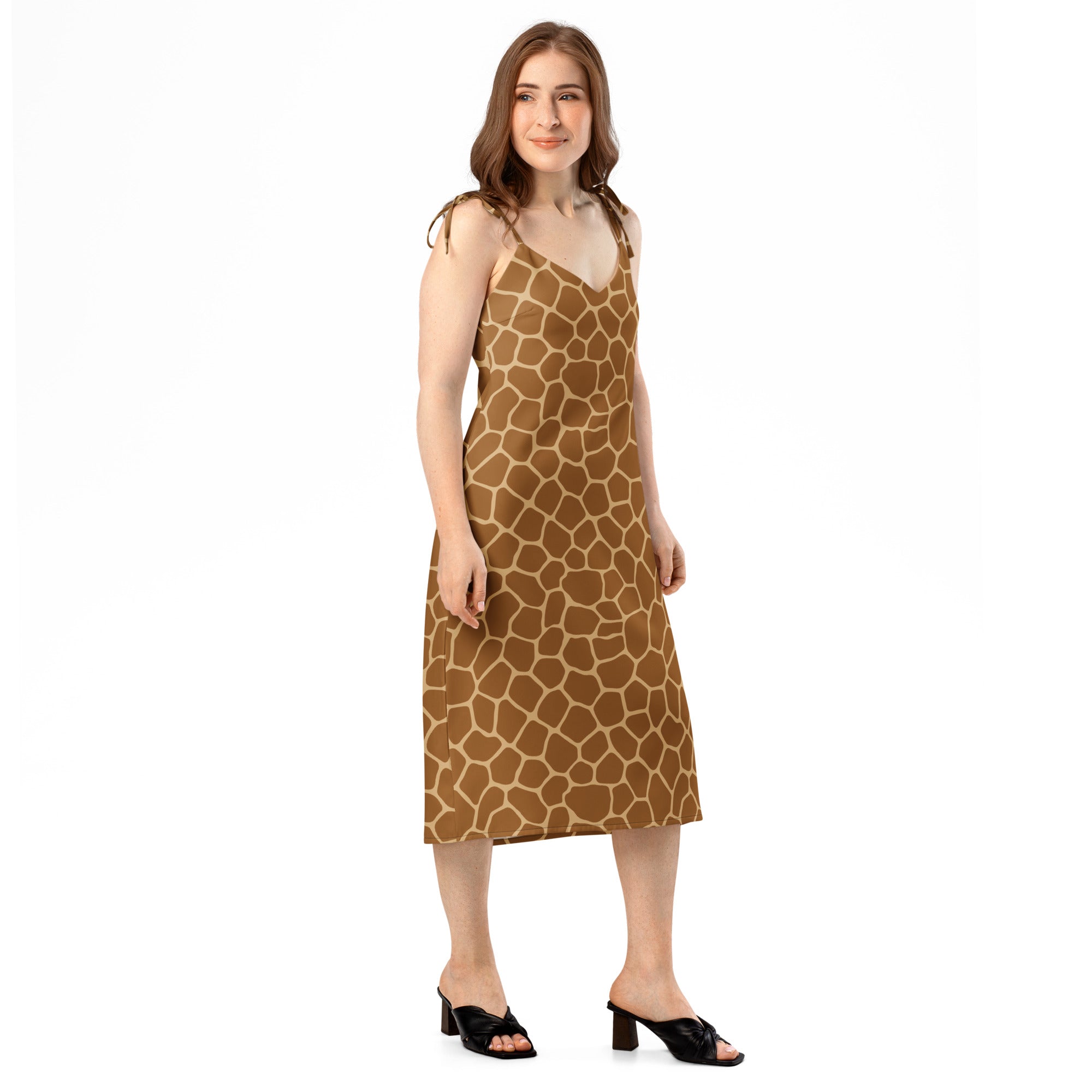 A woman wearing a sleeveless midi giraffe print slip dress with adjustable tie straps and built-in bra in brown and cream