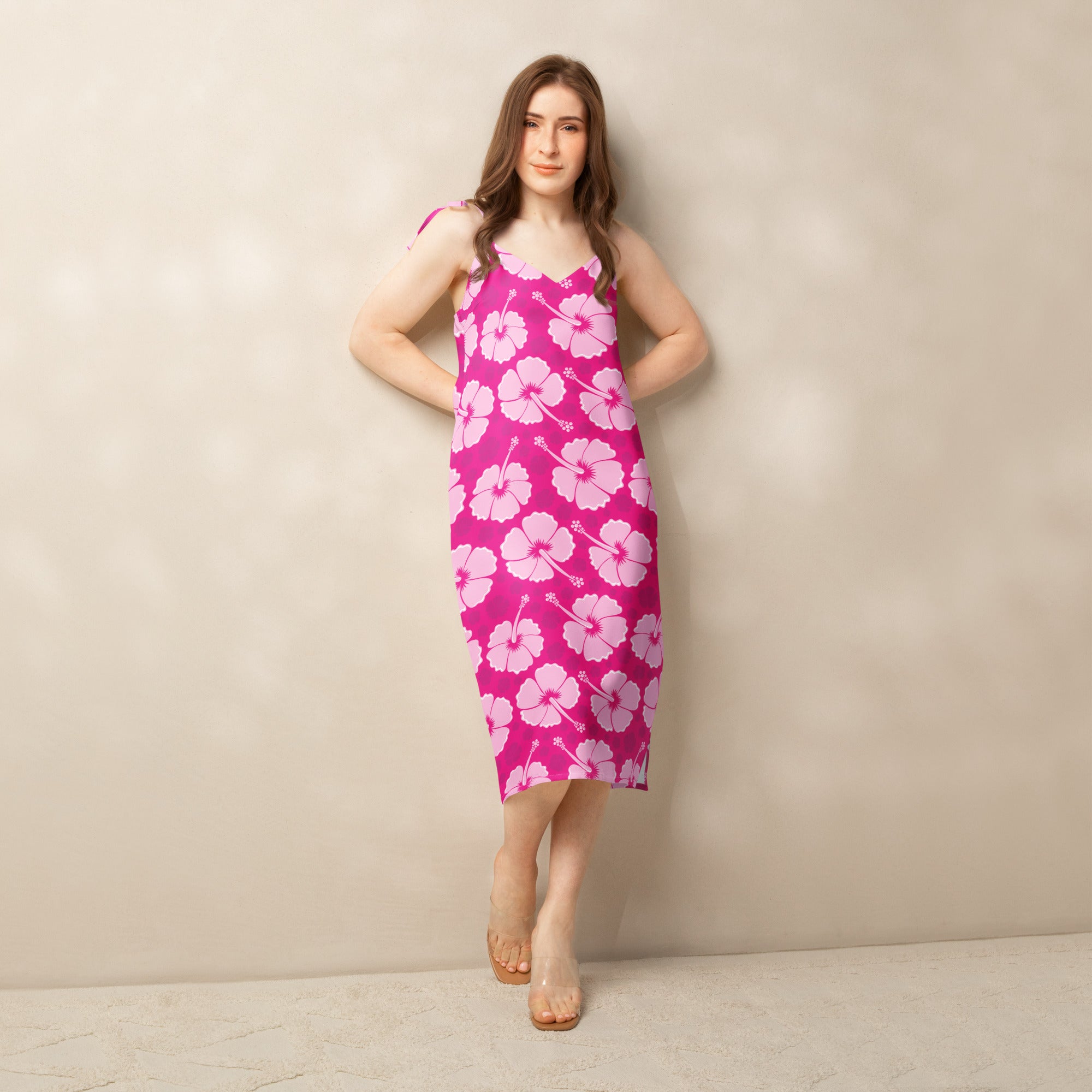 A vibrant pink sleeveless midi slip dress with white hibiscus pattern adjustable tie straps and built in bra