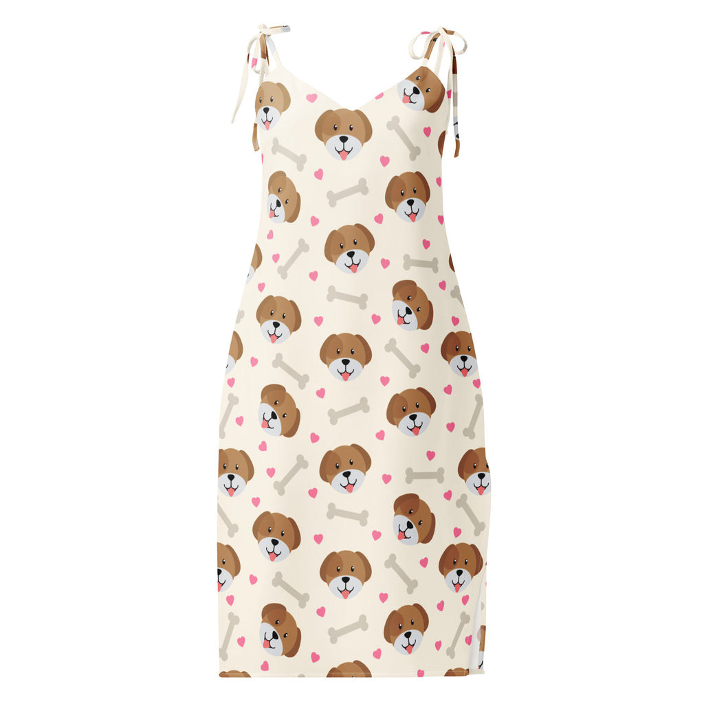 A cream-colored women’s midi slip dress with adjustable tie straps featuring brown dog faces pink hearts and beige bones pattern