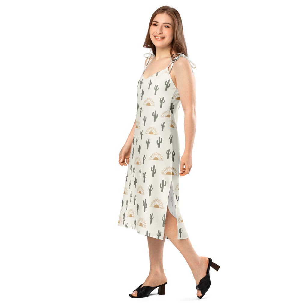 A woman wearing a light-colored sleeveless midi desert cactus sunrise slip dress with adjustable tie straps and built-in bra
