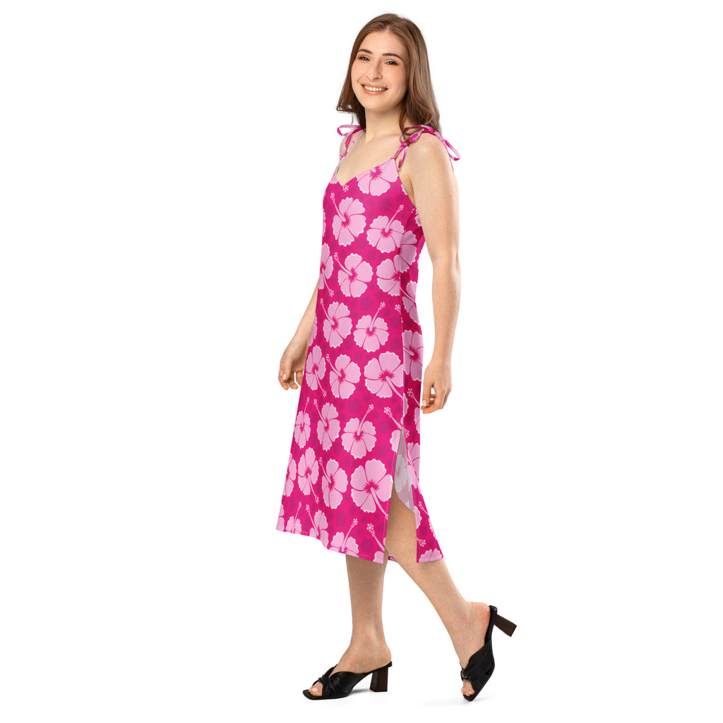 A vibrant pink women’s tropical hibiscus slip dress with bold white flowers, adjustable tie straps, and side slit midi design