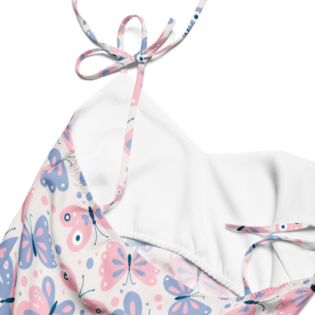 White halter top bikini with pink and blue butterfly print and adjustable tie straps on a light background