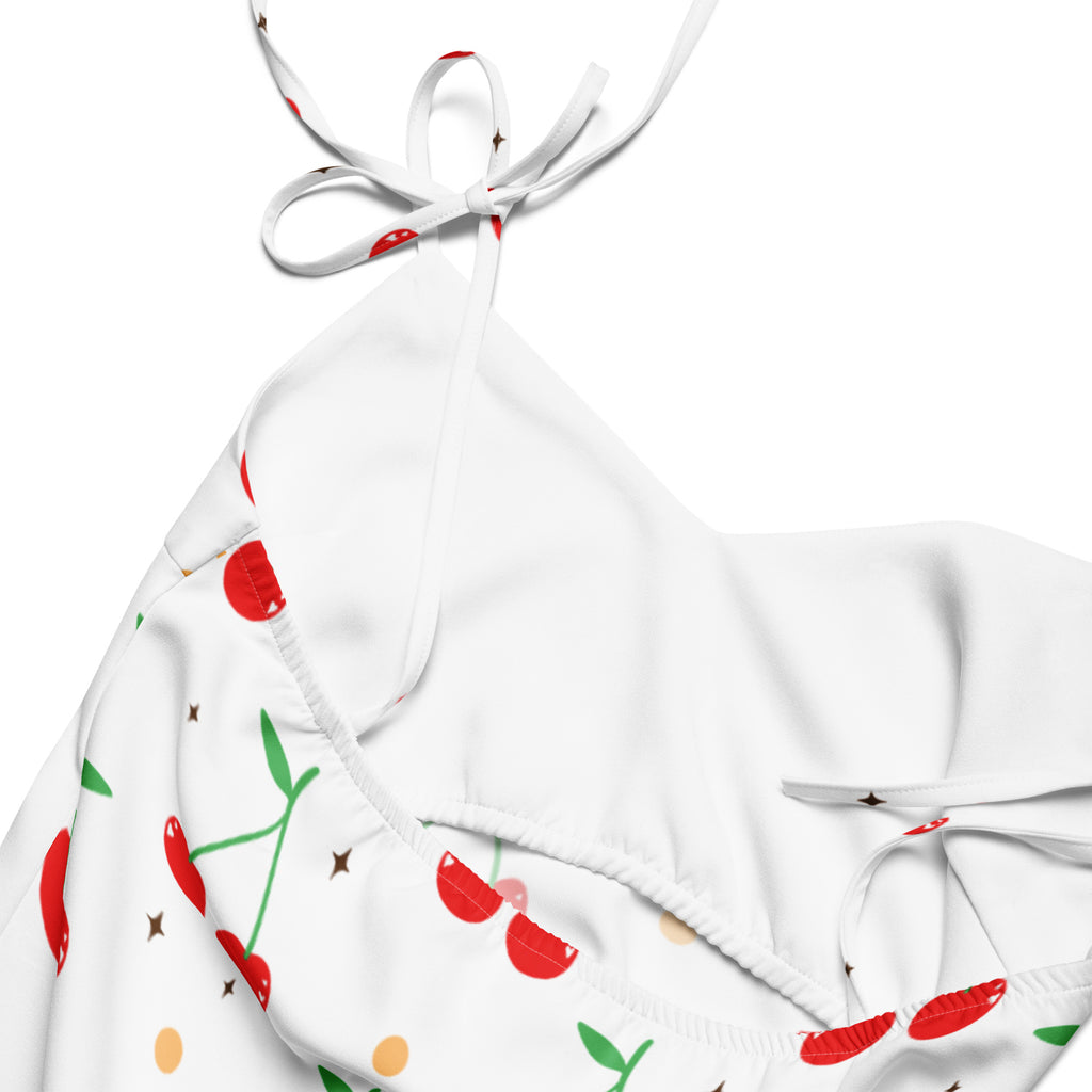 White halter top bikini with cherry and star print in red green and gold paired with women’s cherry print slip dress