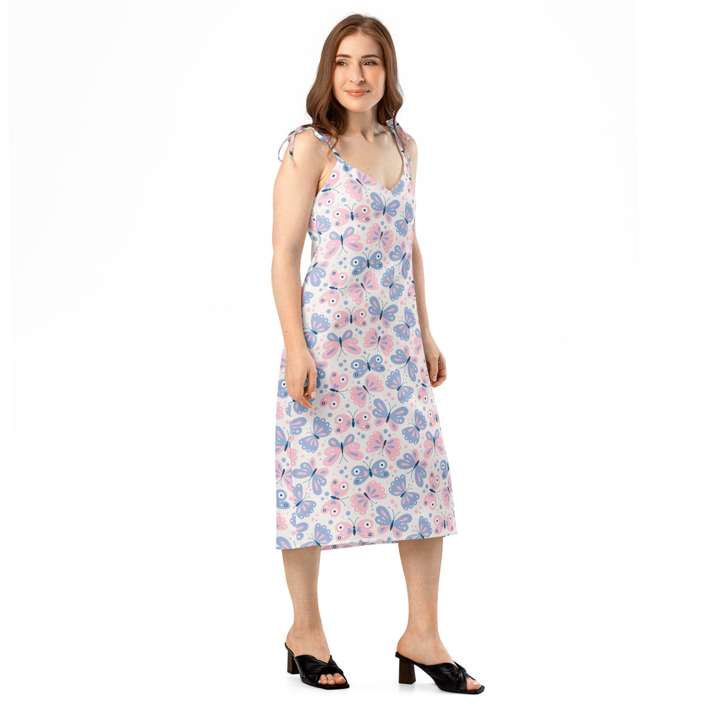A woman wearing a white sleeveless midi butterfly print slip dress with adjustable tie straps and built-in bra