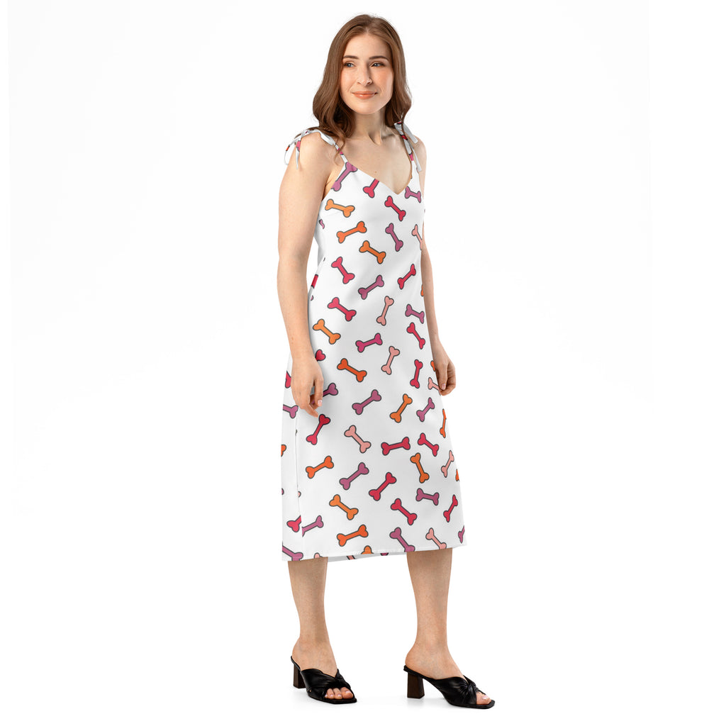 A white sleeveless midi slip dress with multicolored pink orange purple bone pattern and adjustable tie straps