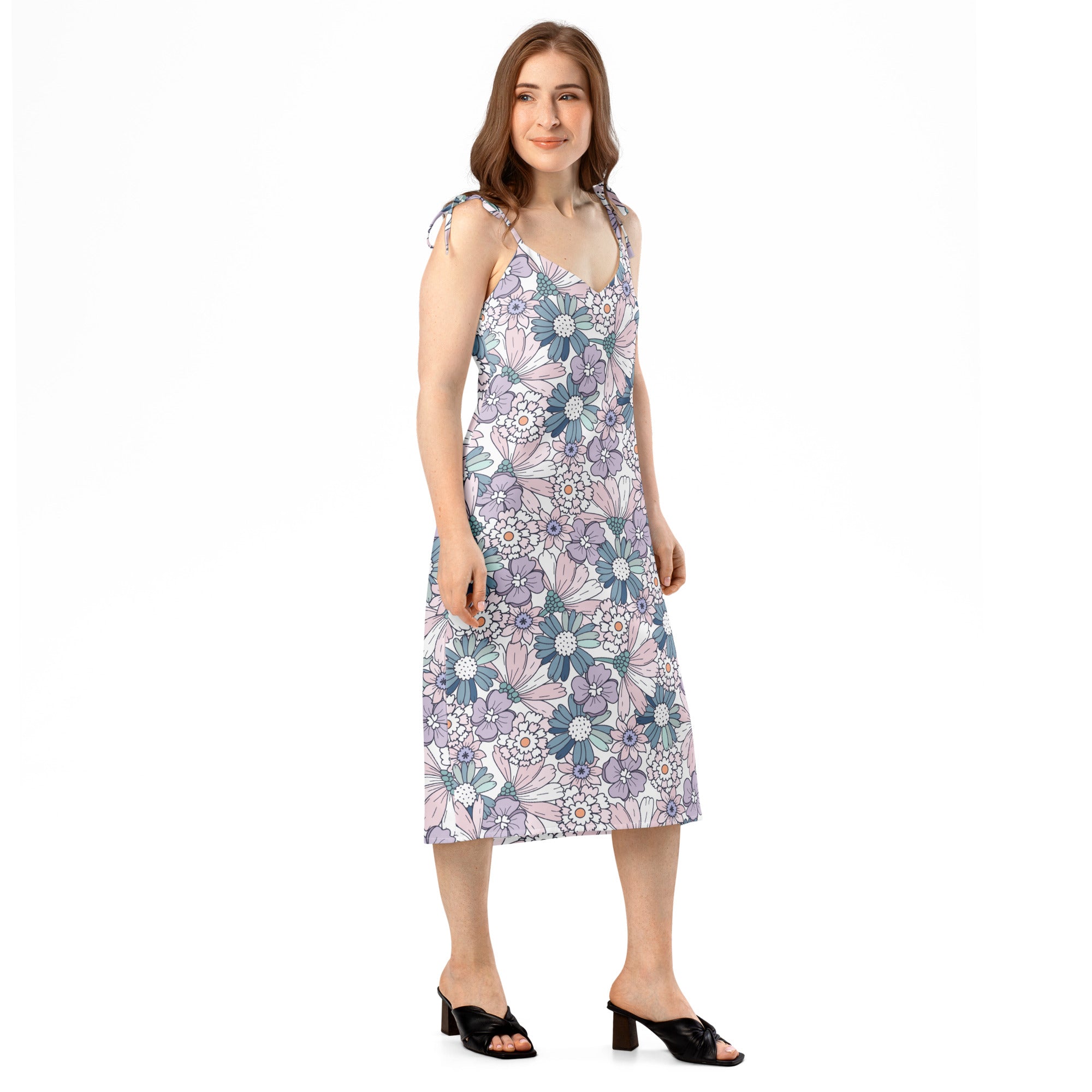 A woman wears a pastel floral slip dress with adjustable tie straps and built in bra in lavender and blue tones