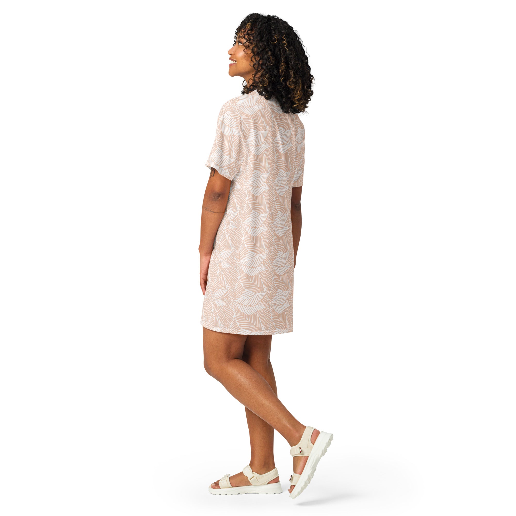 A woman wearing a women’s beige palm leaf t-shirt dress with short sleeves and a subtle white leaf pattern