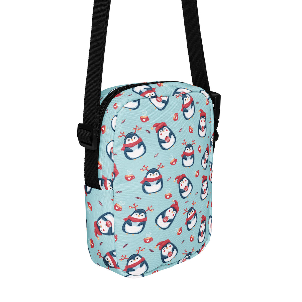 Girls reindeer penguin crossbody purse in light blue with playful cartoon penguins wearing red scarves and hats pattern