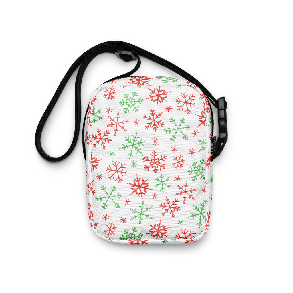 A white girls crossbody purse with red and green snowflake pattern and black adjustable straps