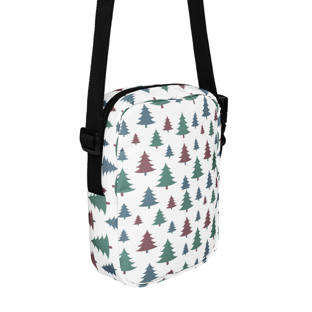 White crossbody bag with green and maroon pine tree pattern and black straps for winter christmas use