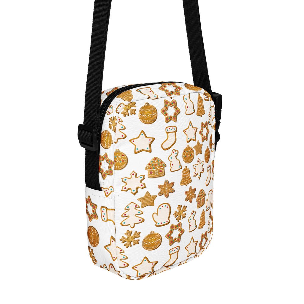 White crossbody bag with black strap featuring gold gingerbread cookies and holiday ornaments festive pattern