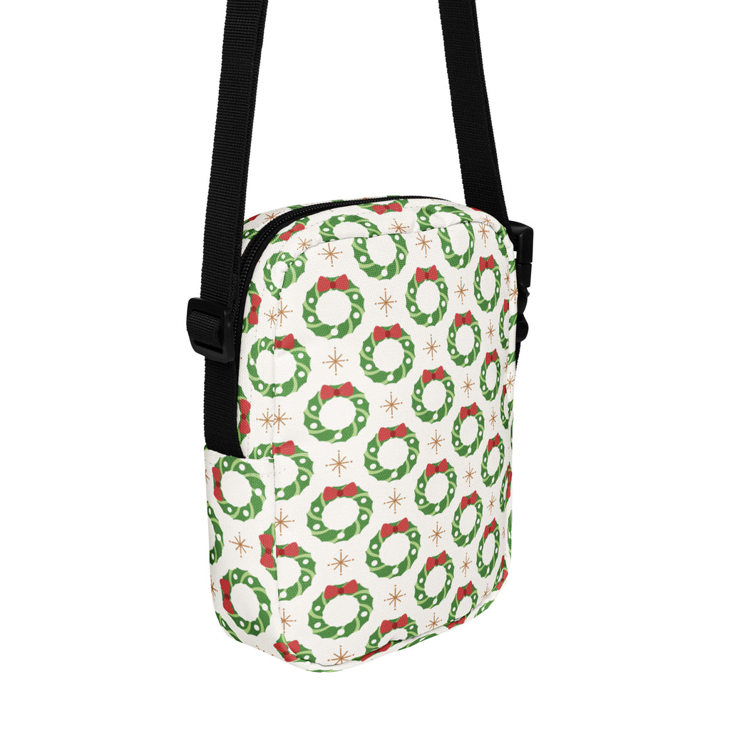 White crossbody bag with festive green wreaths red bows and gold starbursts for christmas use