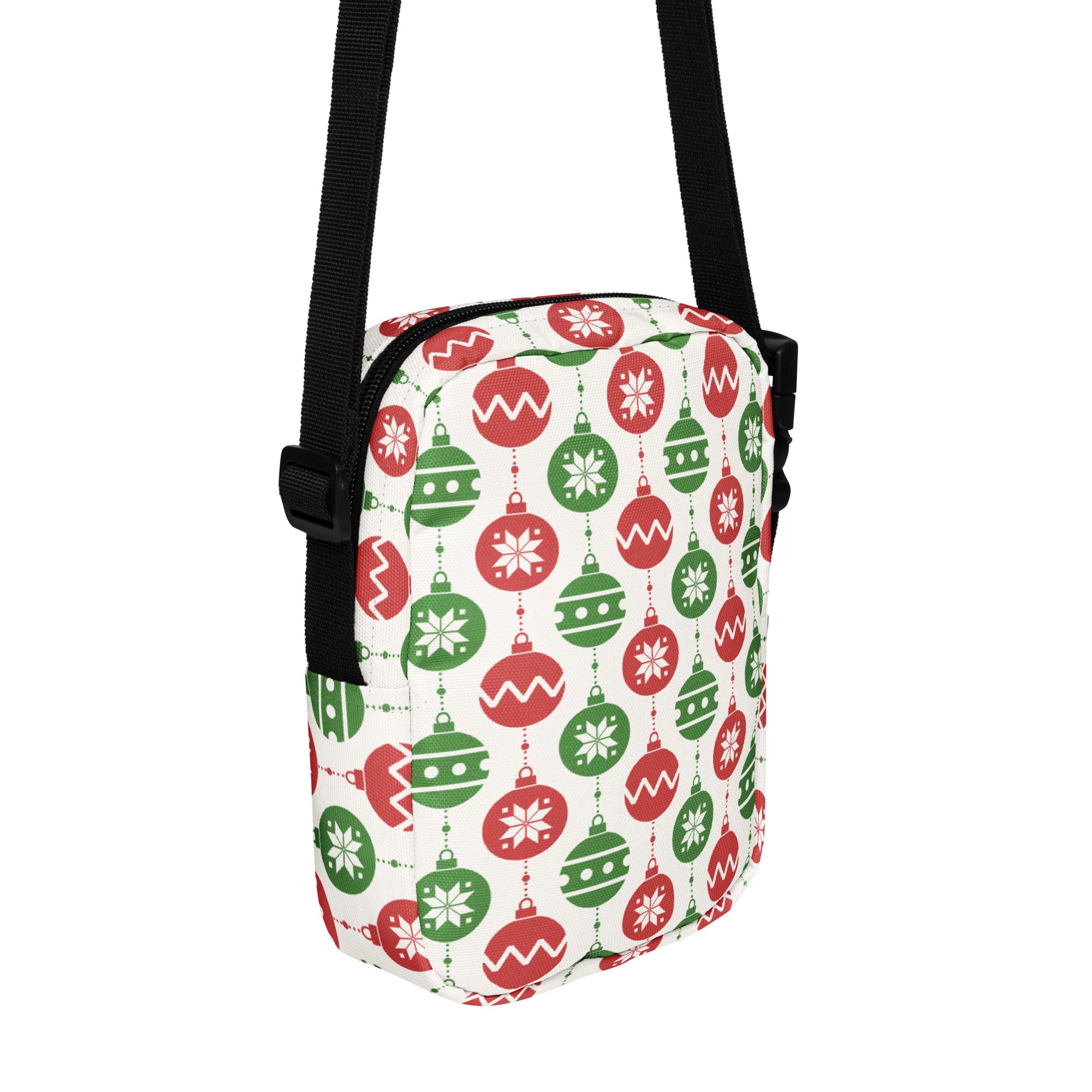 A festive white fabric crossbody purse with red and green christmas ornament patterns and black adjustable straps