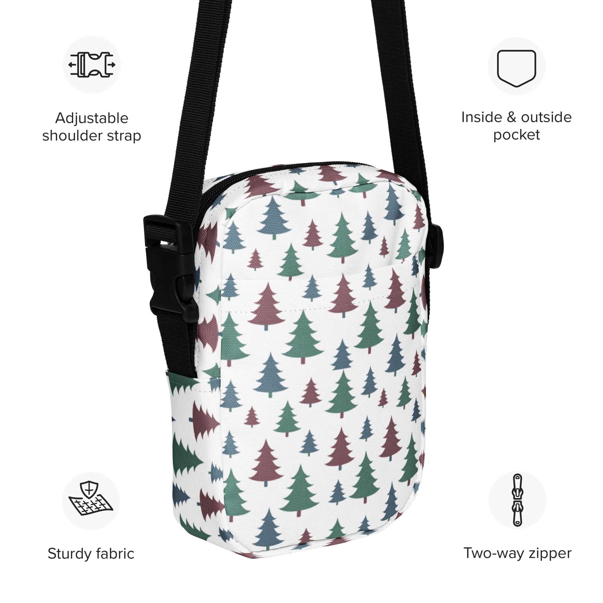 White crossbody bag with green and maroon pine tree pattern and black adjustable straps for winter use