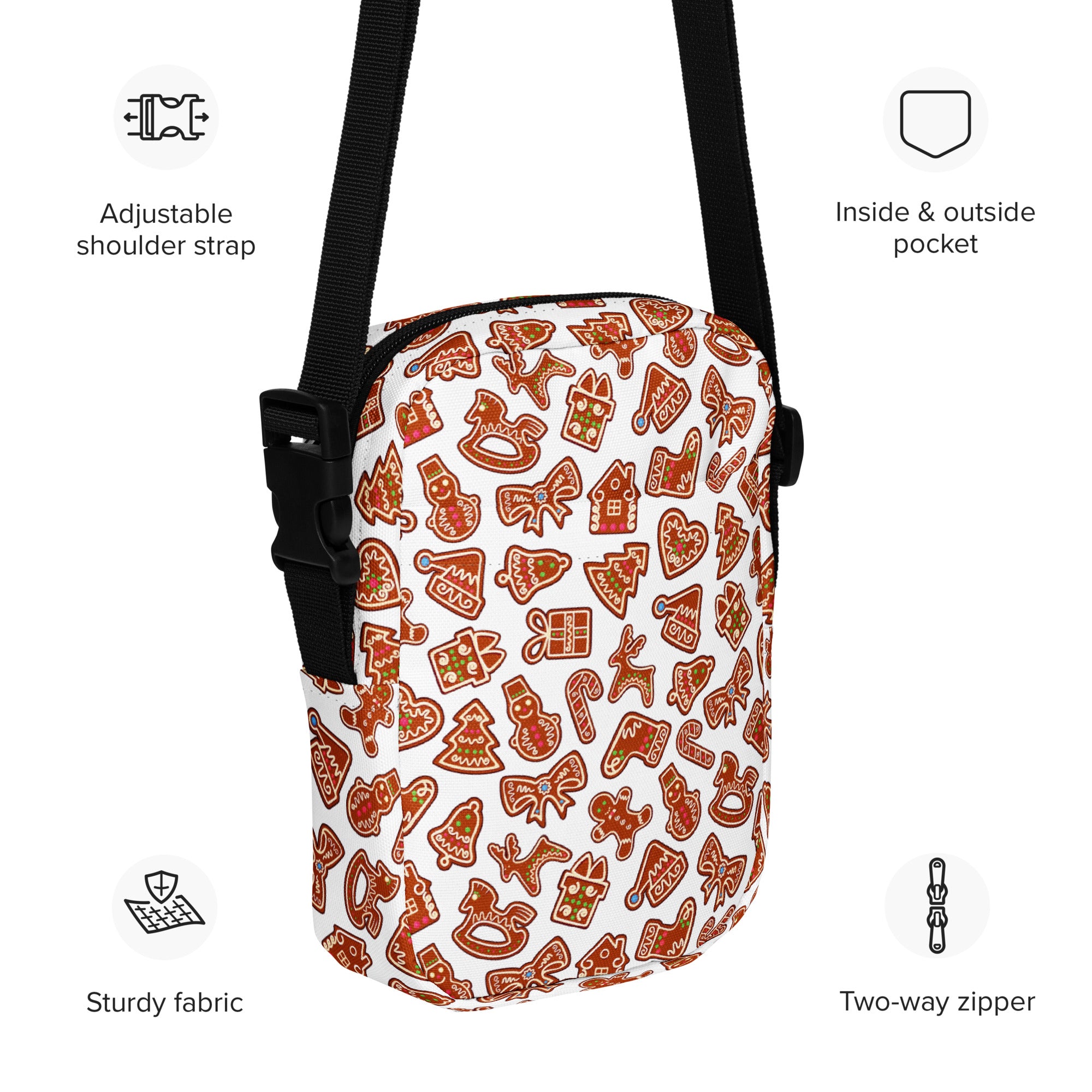 A white crossbody bag with festive gingerbread cookie pattern in brown and red featuring black adjustable straps