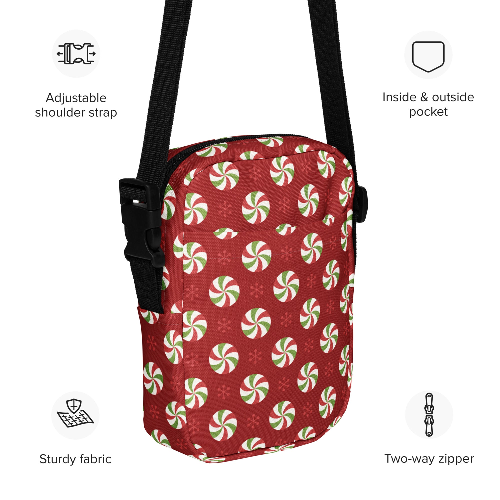Red crossbody bag with festive green and white peppermint candies and snowflakes pattern, black straps, two-way zipper