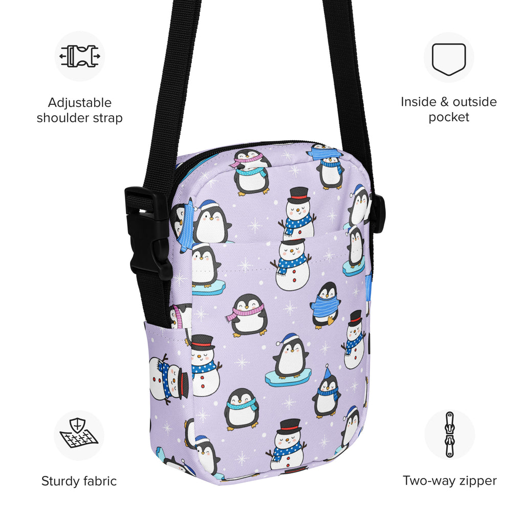 Lavender girls winter penguin crossbody purse with playful cartoon penguins and snowmen wearing scarves and hats