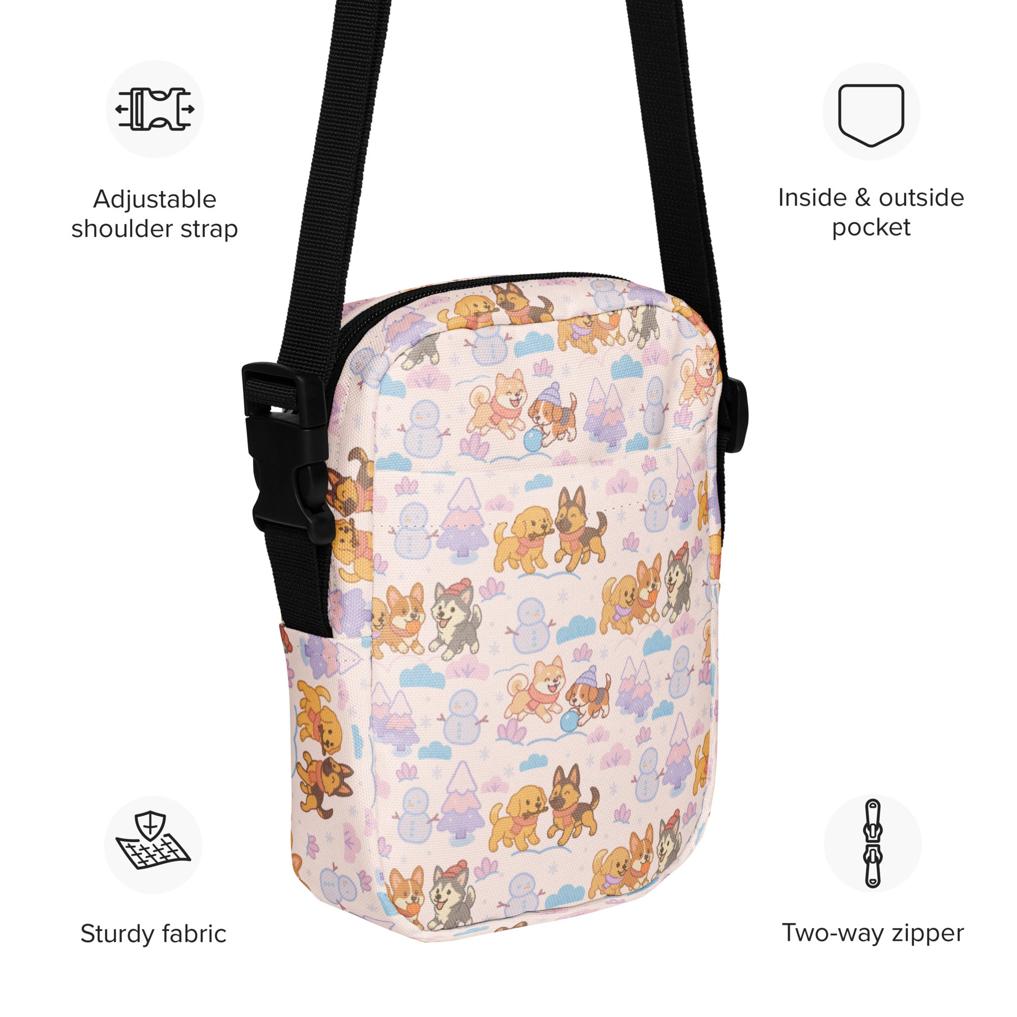 A pink crossbody purse with a playful pattern of cartoon dogs snowmen and trees for cute christmas style