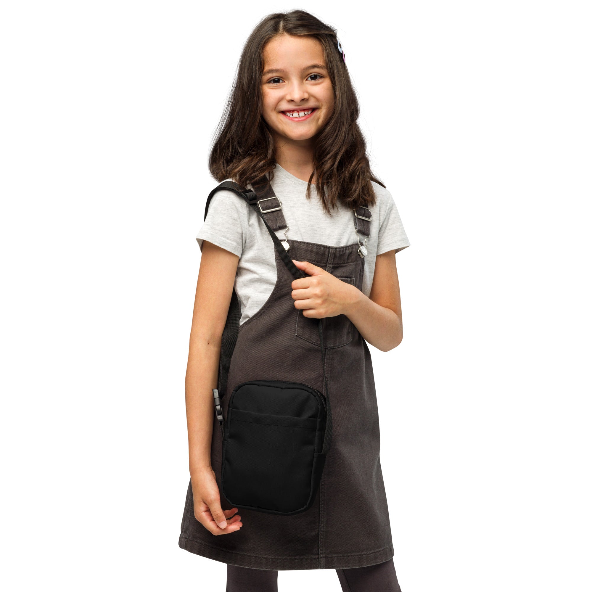 Dark gray denim overall dress with black front pocket and adjustable straps paired with girls black crossbody purse