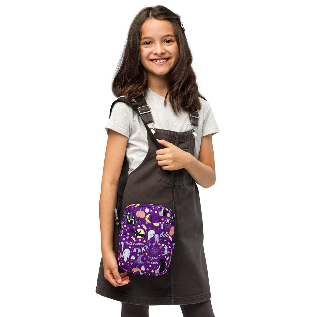 Girls spooky halloween crossbody purse in purple fabric with black straps featuring ghosts bats moons and trick or treat design