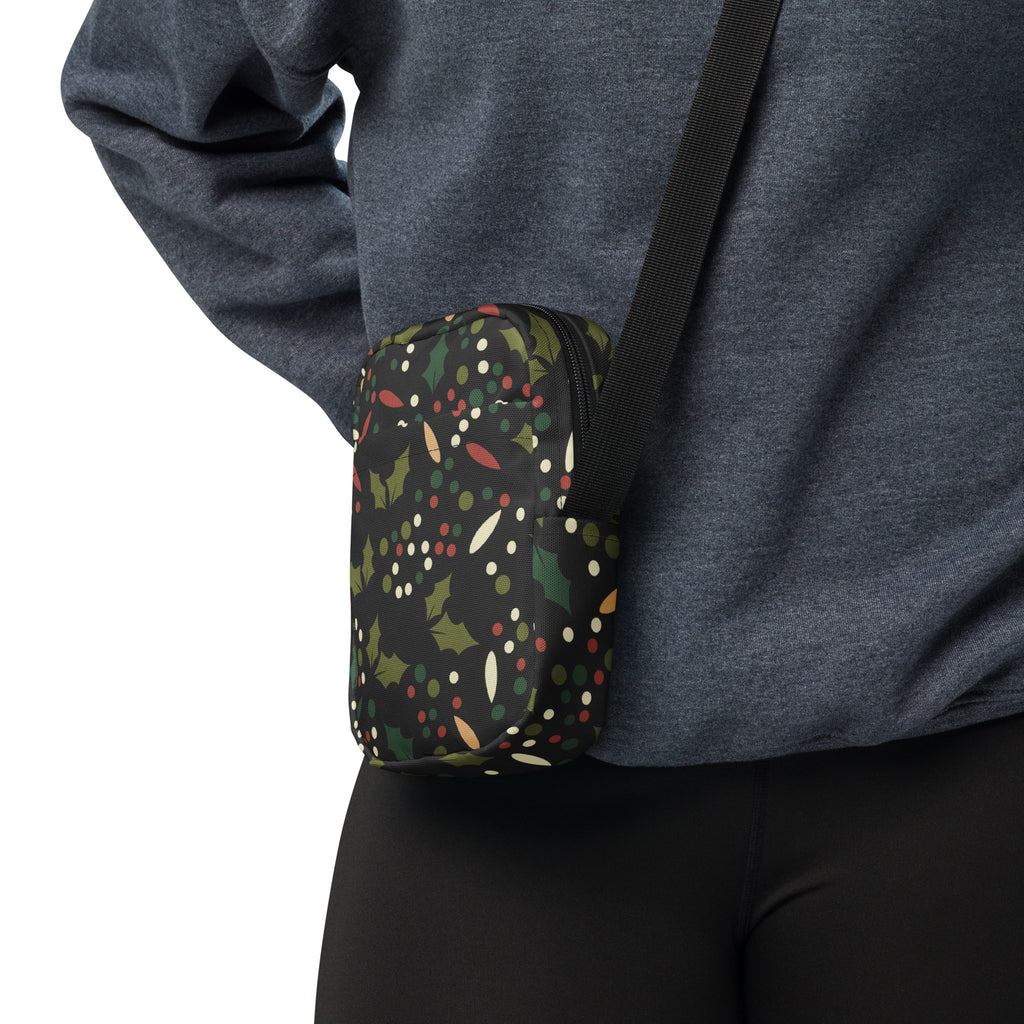 Black crossbody pouch with red Christmas holly berries and green leaves festive pattern on dark background