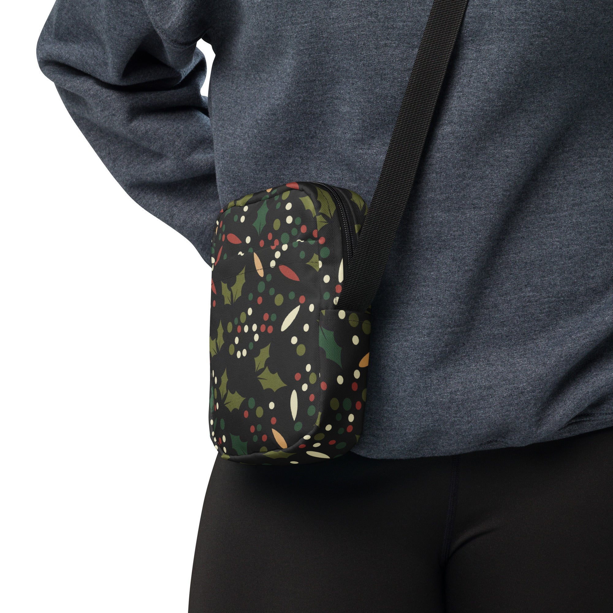 Black crossbody pouch with red Christmas holly berries and green leaves festive pattern on dark background