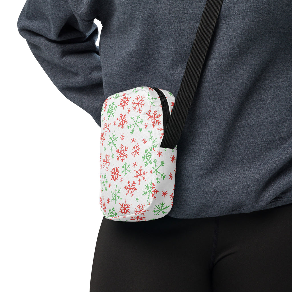 A white crossbody bag with red and green snowflake pattern black zipper and strap for Christmas use