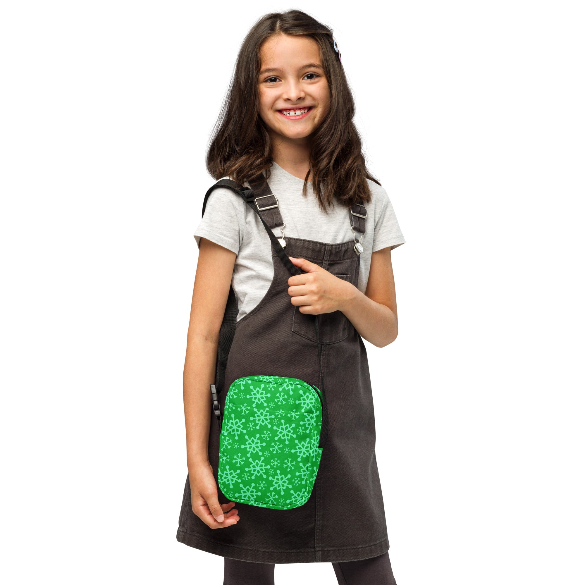 Girls green snowflakes crossbody purse with green snowflake patterned pocket on dark denim overalls