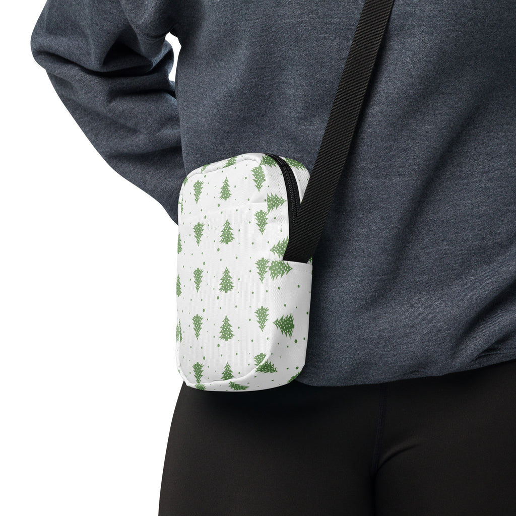 White crossbody bag with green pine tree pattern black zipper and strap designed for winter and christmas use
