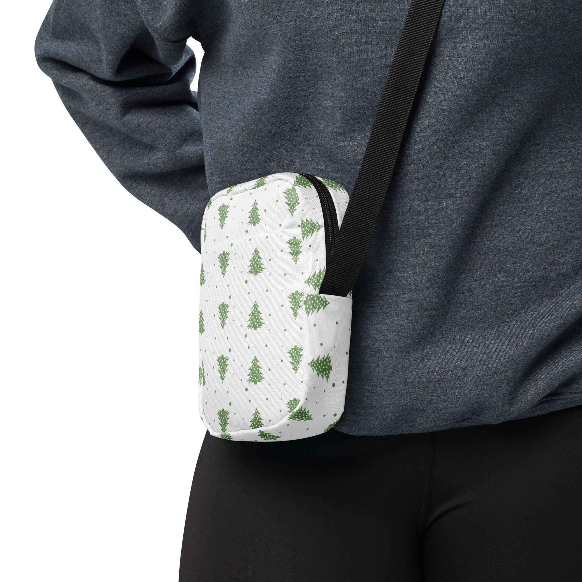 White crossbody bag with green pine tree pattern black zipper and strap designed for winter and christmas use