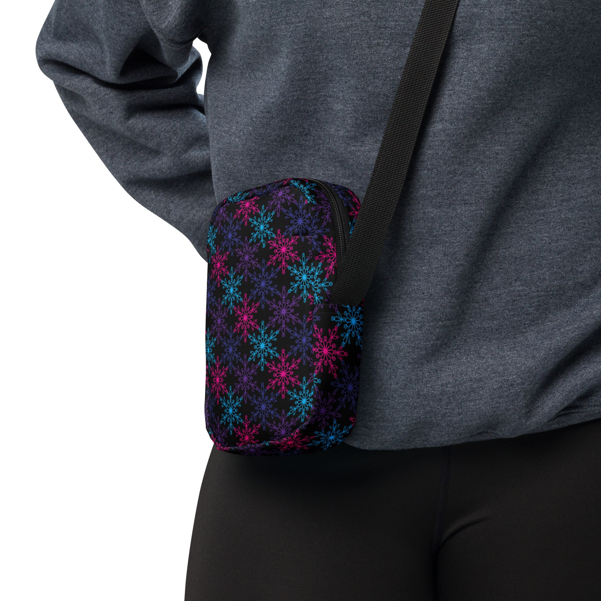 A compact black crossbody pouch with vibrant neon pink and blue snowflake patterns for winter women’s use