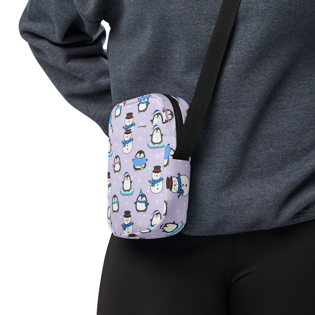 Lavender crossbody pouch featuring a playful pattern of cartoon penguins and snowmen in winter outfits