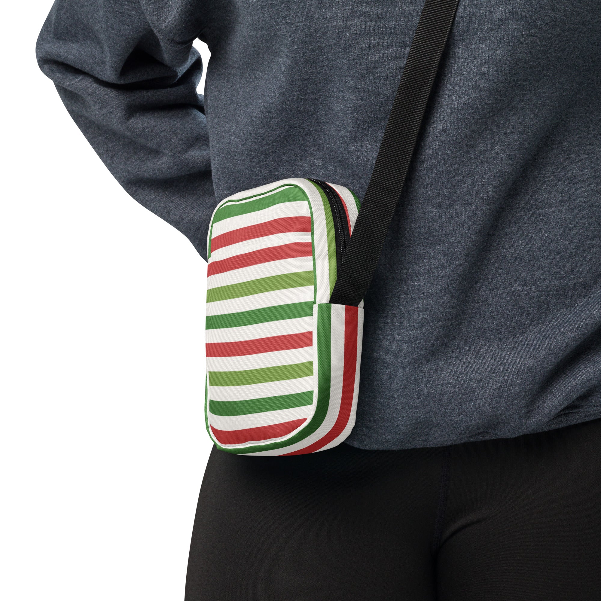 A compact Christmas striped women’s crossbody purse with red white and green stripes and a black adjustable strap
