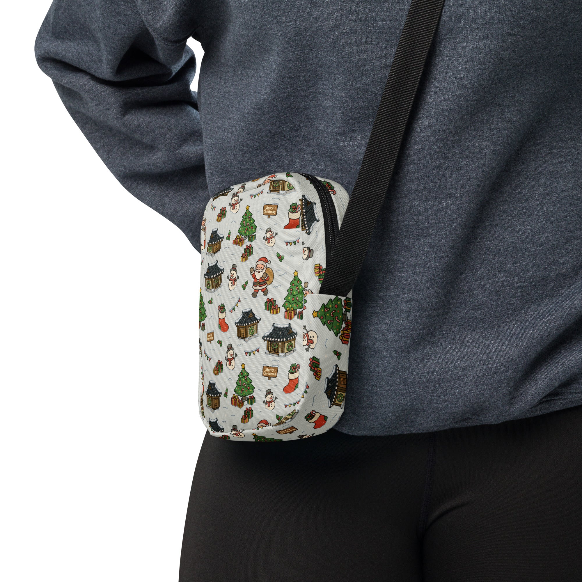 A festive white crossbody pouch featuring a holiday pattern with santa snowmen christmas trees and houses