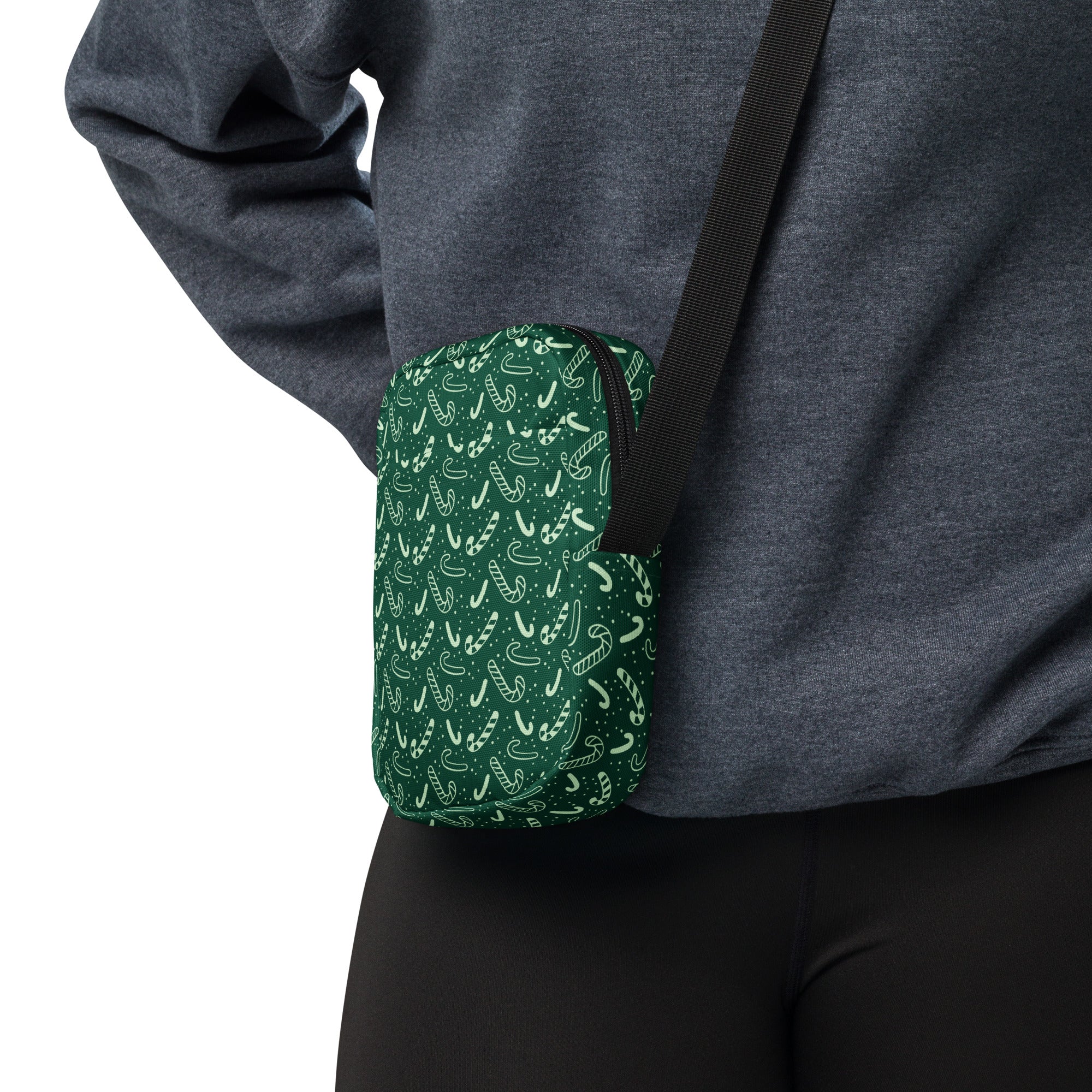 Green candy cane patterned crossbody pouch with black strap for women featuring festive holiday design