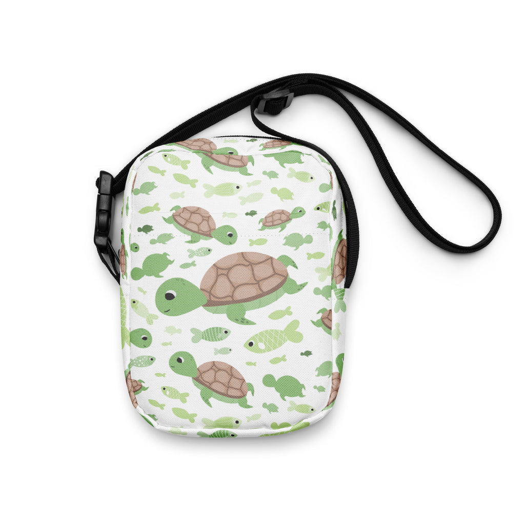 White crossbody bag with green and brown cartoon sea turtles and fish pattern and black adjustable straps for girls