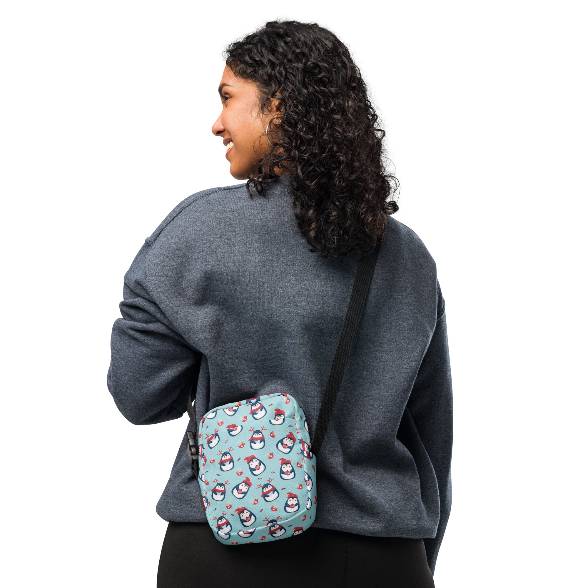 Teal crossbody purse with playful penguin pattern wearing red hats and scarves for women by Reindeer Penguin