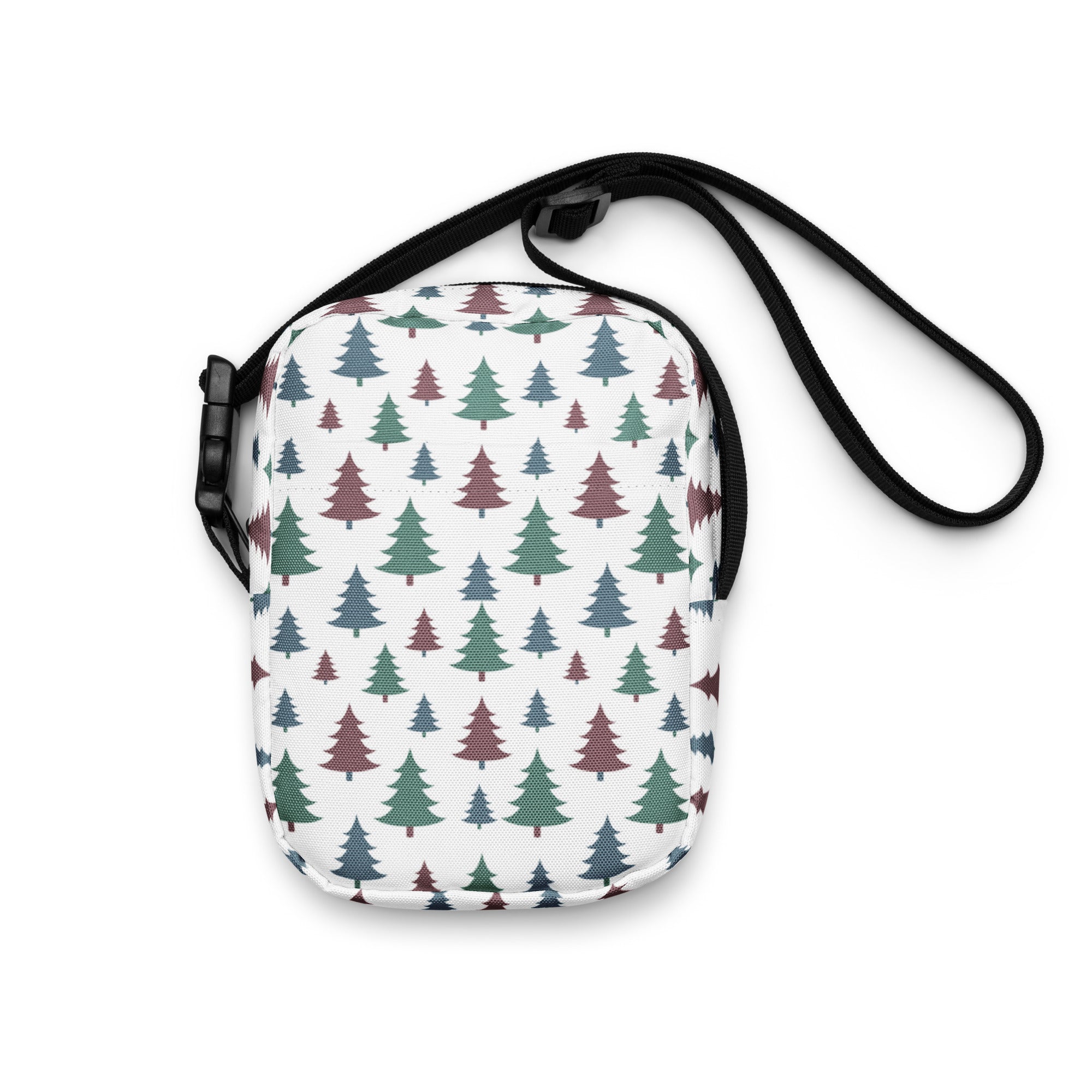A white crossbody purse with green and maroon evergreen tree pattern and black adjustable strap for winter use
