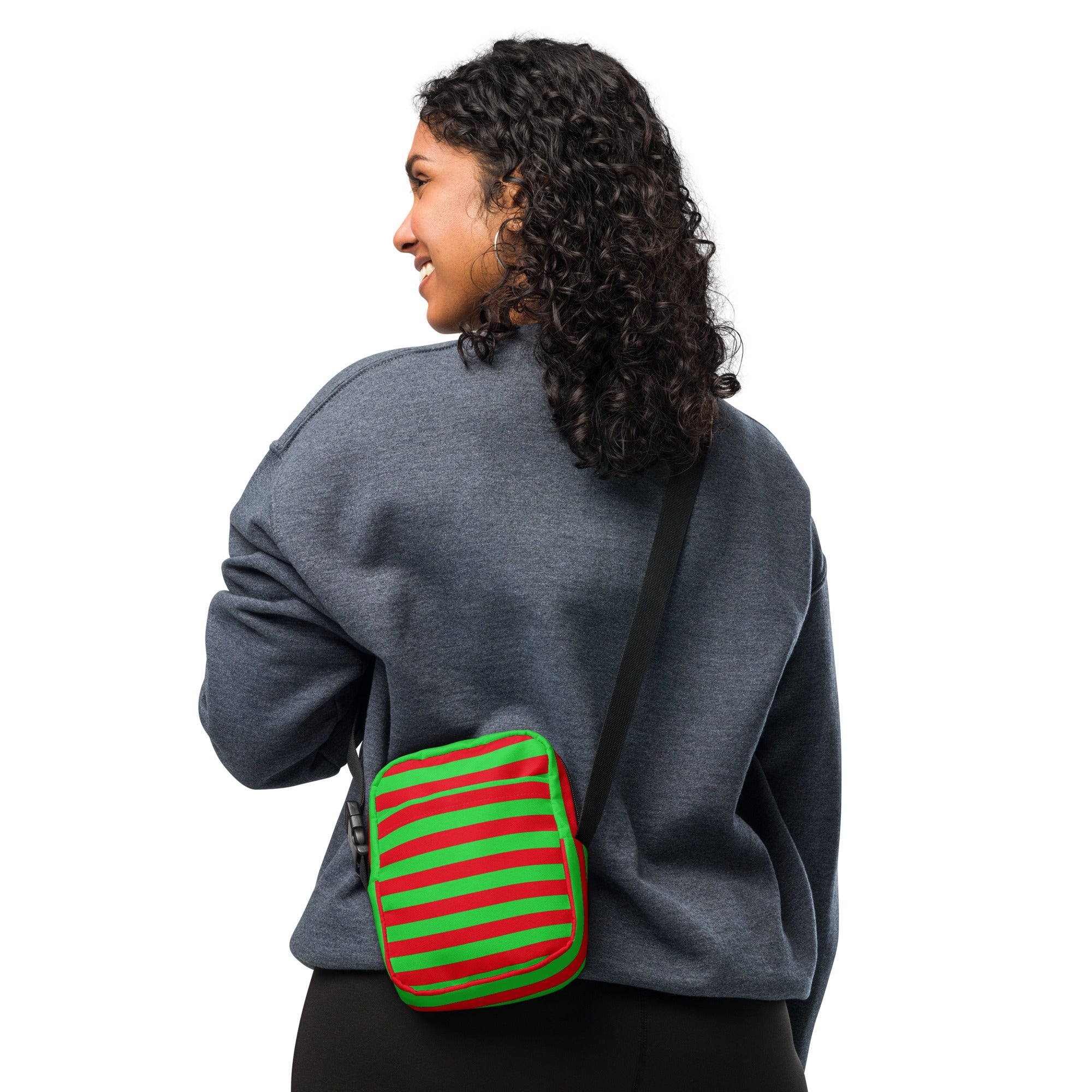 A vibrant red and green striped christmas women’s crossbody purse with a black adjustable strap