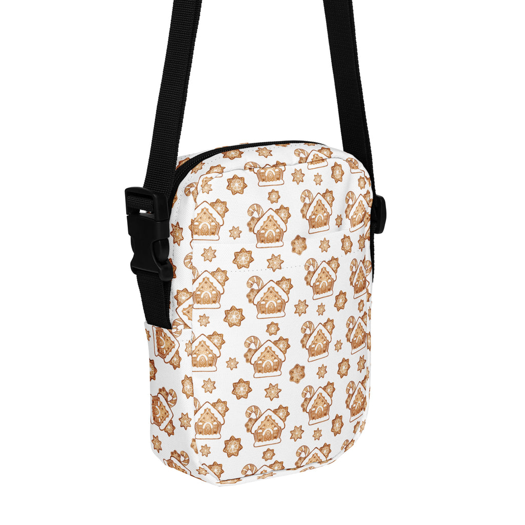 White crossbody purse with festive gingerbread house and star pattern in warm brown tones and black adjustable straps