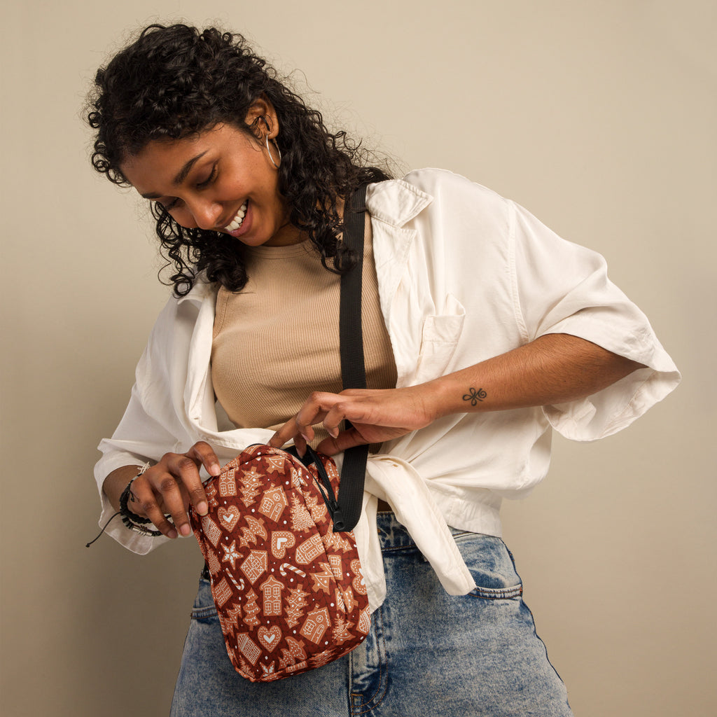 A festive brown fabric crossbody bag with gingerbread houses hearts and candy canes pattern for christmas use