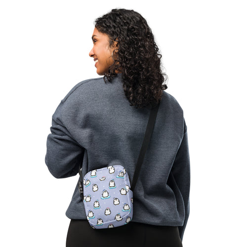 A light purple women’s crossbody purse with playful cartoon penguins and blue accents for cute winter style