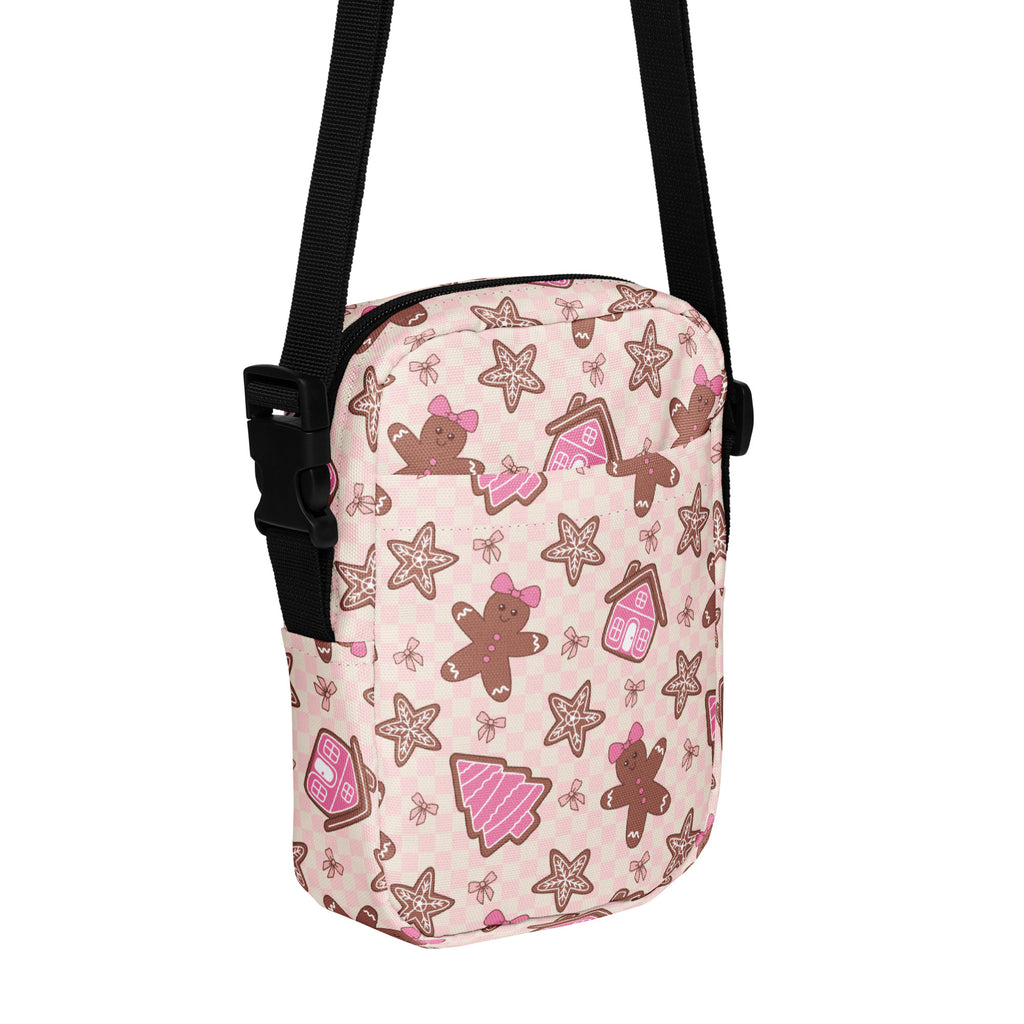 Pink crossbody purse featuring a festive gingerbread men star cookies and houses pattern for christmas use