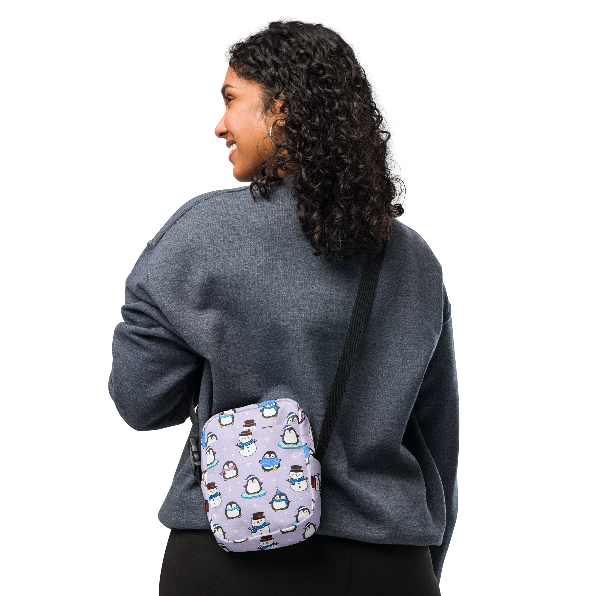 A lavender holiday penguins and snowmen crossbody purse with playful cartoon penguin pattern and adjustable strap