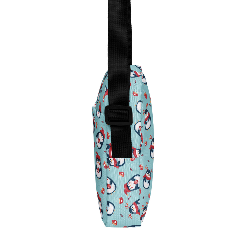 A light blue girls reindeer penguin crossbody purse with cartoon penguins in red scarves and candy motifs