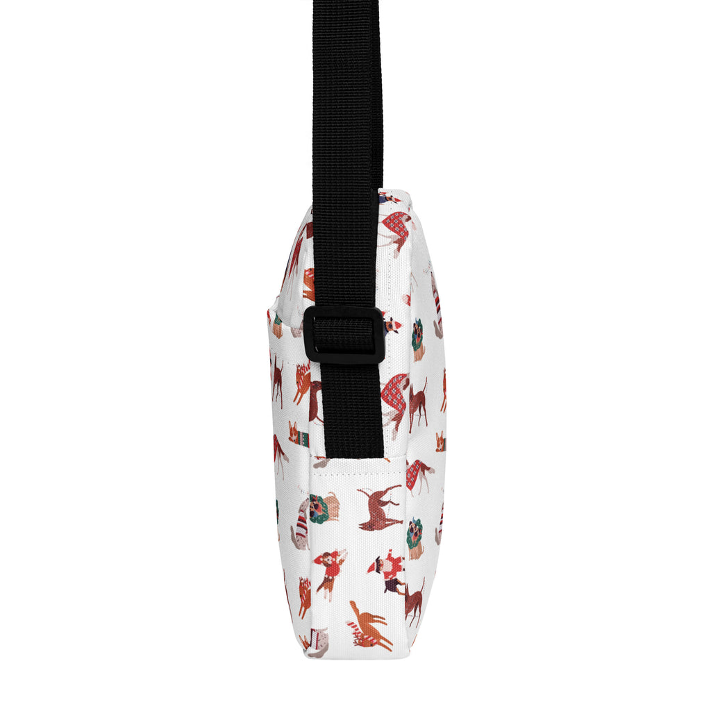White crossbody bag with black strap featuring red brown and green holiday-themed dog illustrations