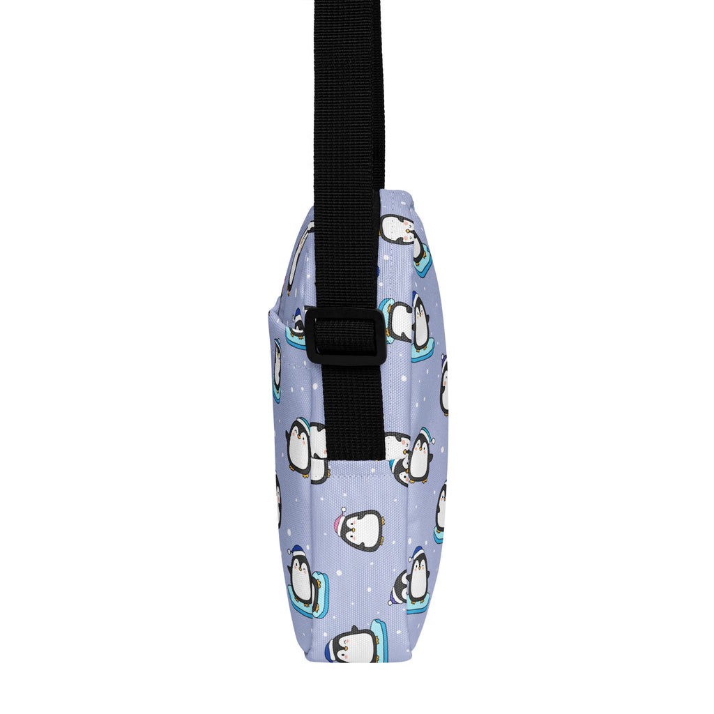 Light purple crossbody bag with playful cartoon penguins on ice skates and black adjustable strap for winter use