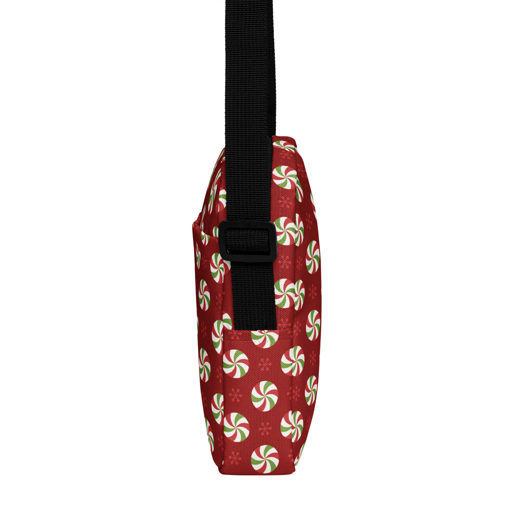 Red girls crossbody purse with red fabric featuring festive green and white peppermint candies and a black strap